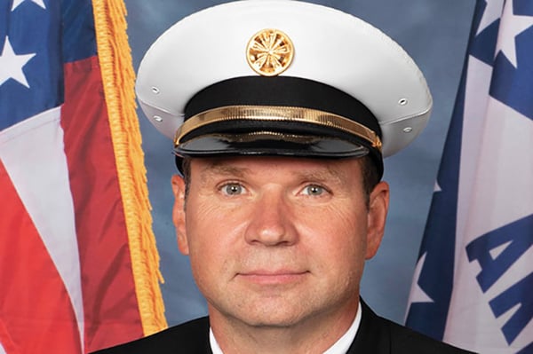 Fayetteville Fire Department Fire Chief posed in front of flags.