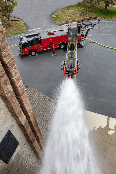 Fire truck with ladder extended spraying water