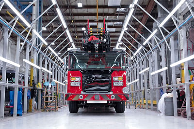 A red and black Pierce fire truck inside the light tunnel on a white floor.