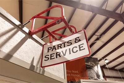 A hanging white sign reading 'parts and service' in black font with a red outline.