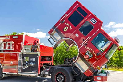 A red Pierce fire truck is parked with the cab lifted showing ease of serviceability for fire truck engine repairs.