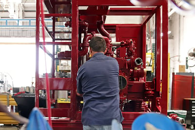 A factory worker assembles the pumphouse of a fire truck.