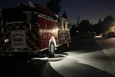 A nighttime photo shows a wildland fire truck on the road with the rear wheel rock lights illuminated, increasing visibility around the apparatus. 