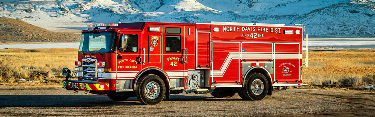 The driver's side of an Enforcer Pumper parked in front of a snow covered mountain.