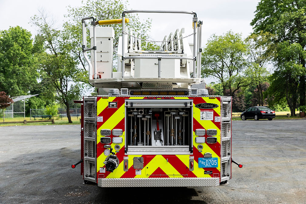 The rear of an aerial ladder with the compartment door open showing ladders storage.