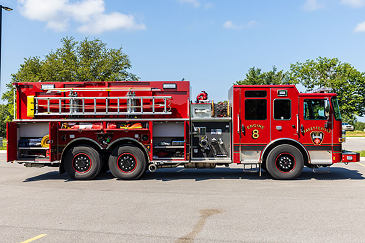 The Officer's side of a Pierce Enforcer Custom Dry-Side Tanker parked in a parking lot with the compartments open showing equipment.