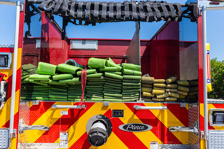 The rear of a Pierce fire truck showing the hosebed with fire hoses stacked in it.