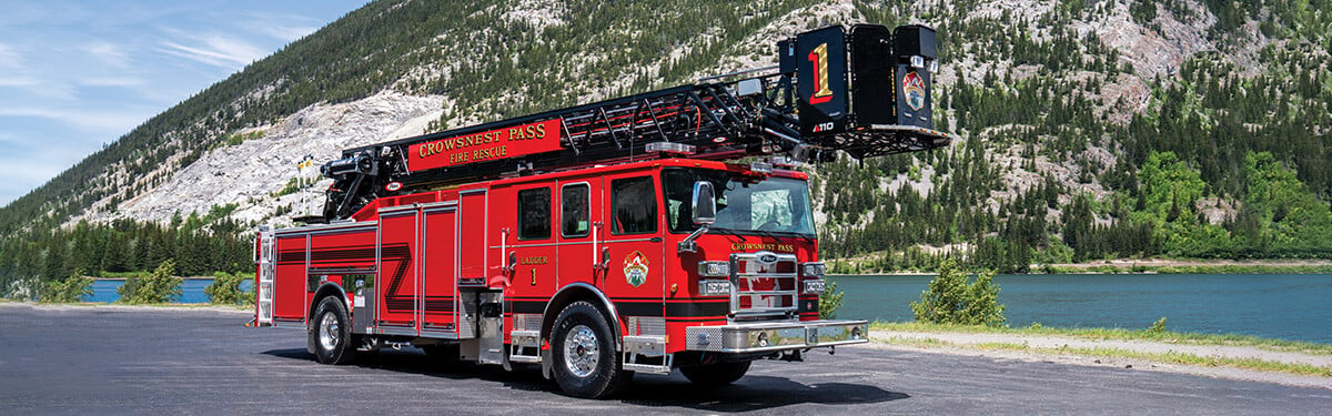 Crowsnest Pass Fire Rescue's Enforcer 110' Ascendant Heavy-Duty Aerial Platform parked in front of a lake and a mountain.