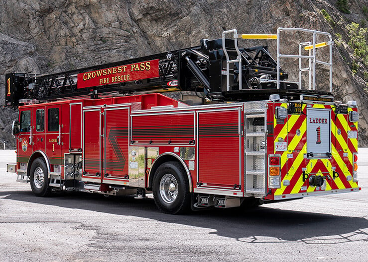 The driver's side rear of an Enforcer 110' Ascendant Heavy-Duty Aerial Platform parked beside a mountain.