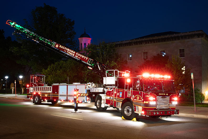 Baltimore County Fire Department's Ascendant 107' Heavy-Duty Tiller Aerial Ladder parked outside at night with the lights on.