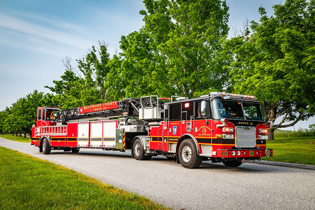 The front officer's side of Baltimore County Fire Department's Ascendant 107' Heavy-Duty Tiller Aerial Ladder parked outside.