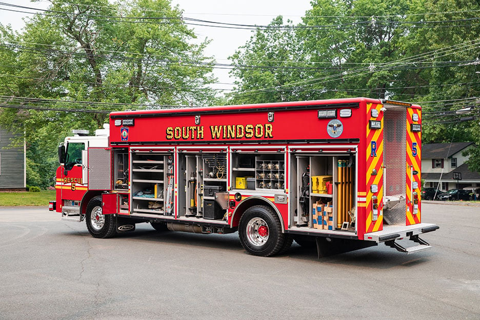 The driver's side of a Velocity Walk-In Heavy-Duty Rescue fire truck with the compartments open showing equipment storage.