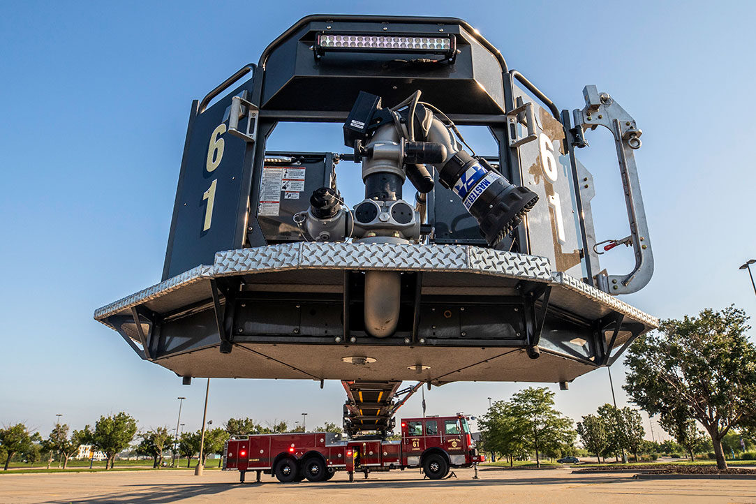 The basket of an Ascendant Aerial Tower extended on the drivers side level with the ground in a parking lot.