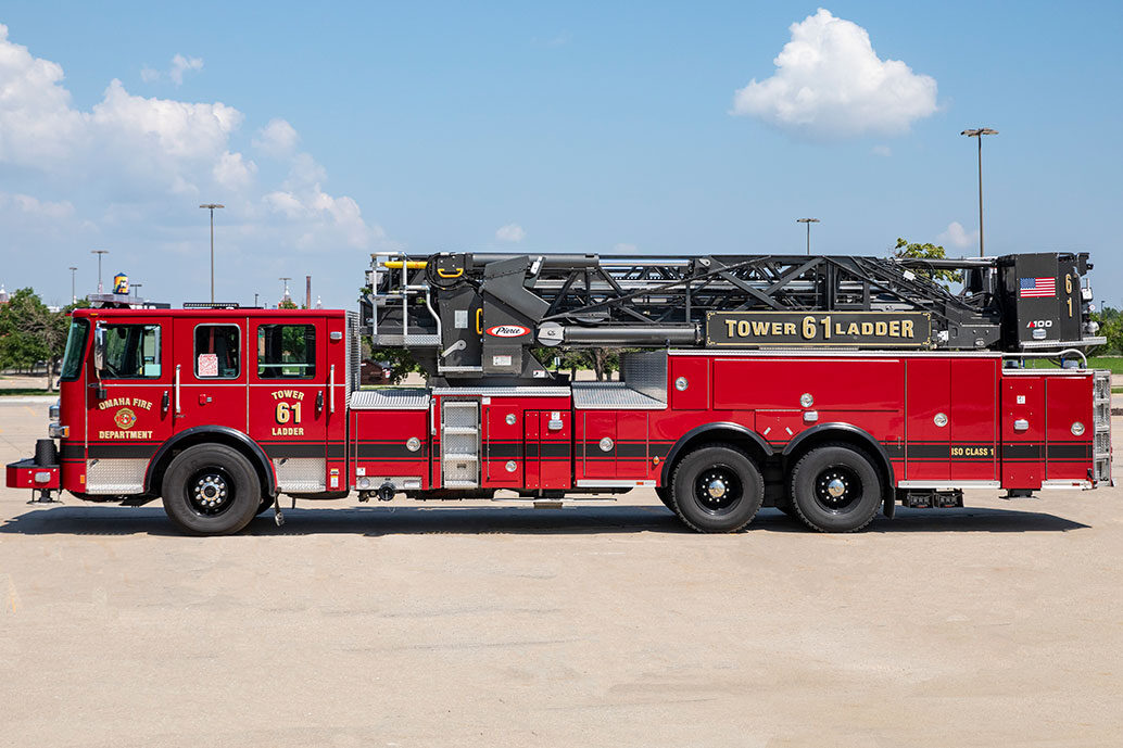 The drivers side of an Enforcer 100 Ascendant Aerial Ladder in a parking lot on a sunny day with clouds in the sky.