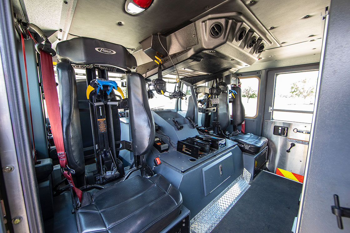 The inside of a fire truck crew cab with two rear facing seats with SCBA holders.