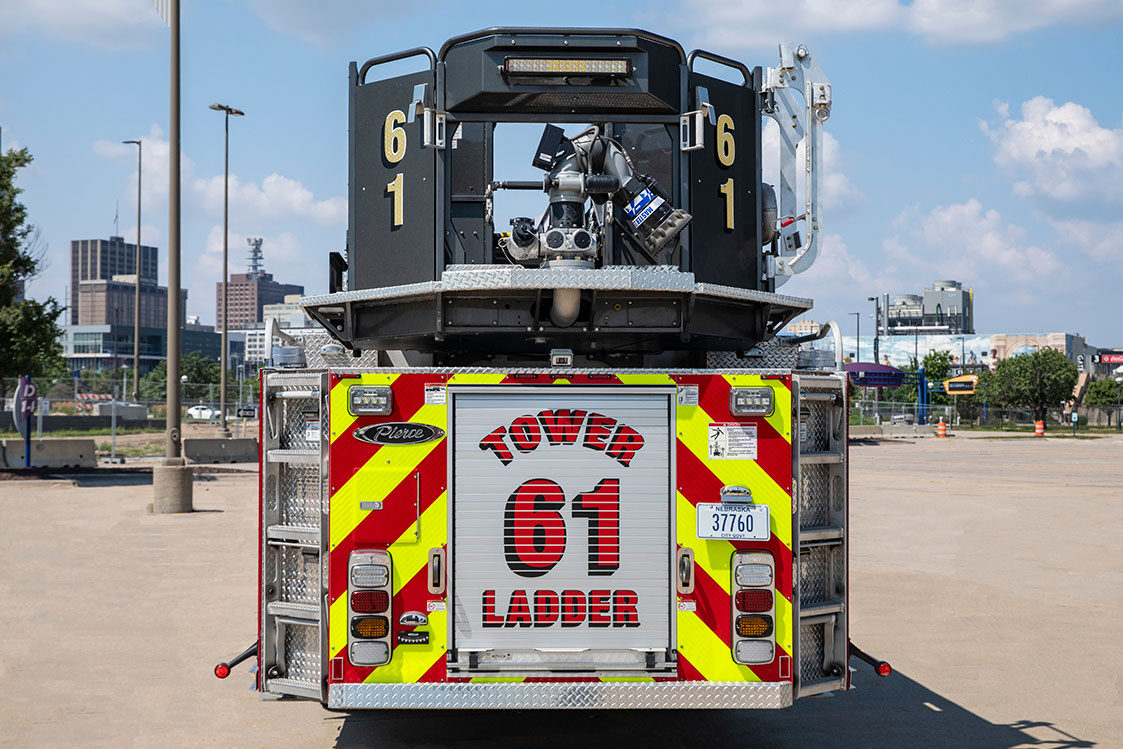 The rear of an Ascendant 100 Aerial Tower in a parking lot on a sunny day with graphics on the rear compartment door.