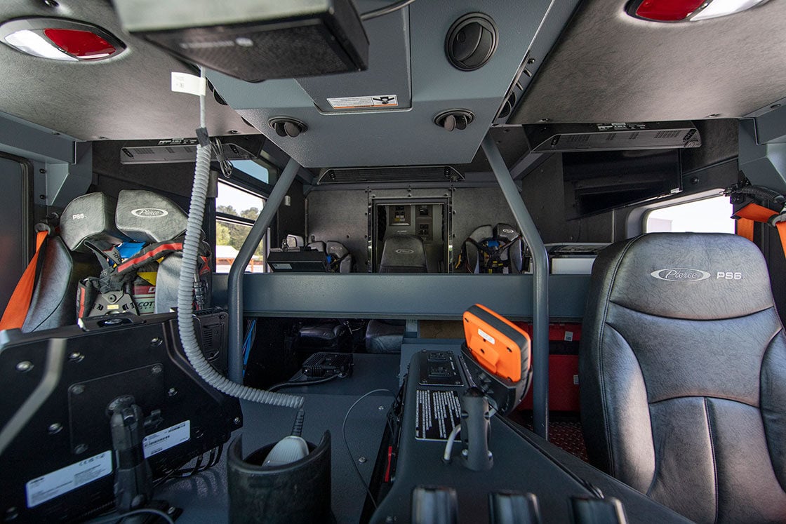 The front seat of a heavy-duty rescue fire truck with a workstation in the back of the crew cab.