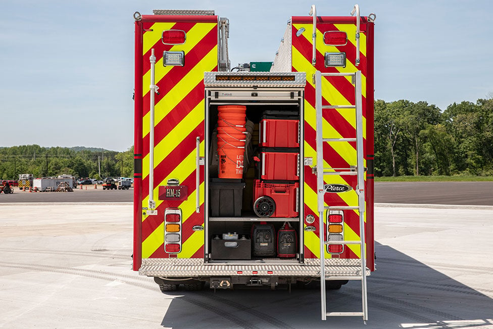 The rear of a Pierce heavy-duty rescue fire truck with the compartment open showing equipment inside.