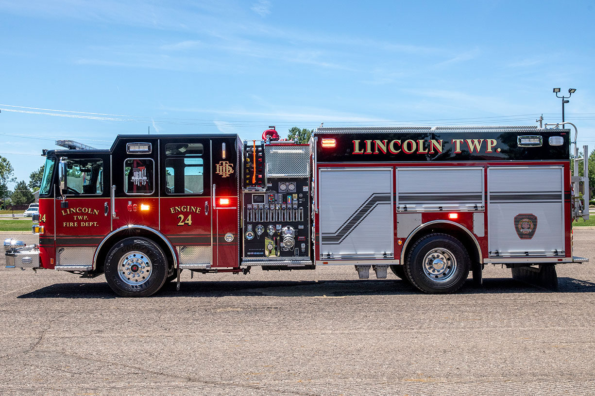 The drivers side of an Enforcer Rescue Pumper with the lights on in an empty parking lot on a sunny day.