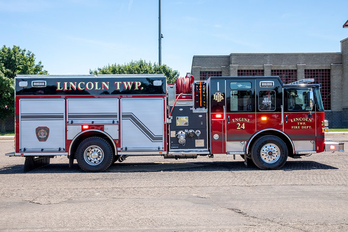 The officers side of an Enforcer Rescue Pumper in front of a brick building on a sunny day.