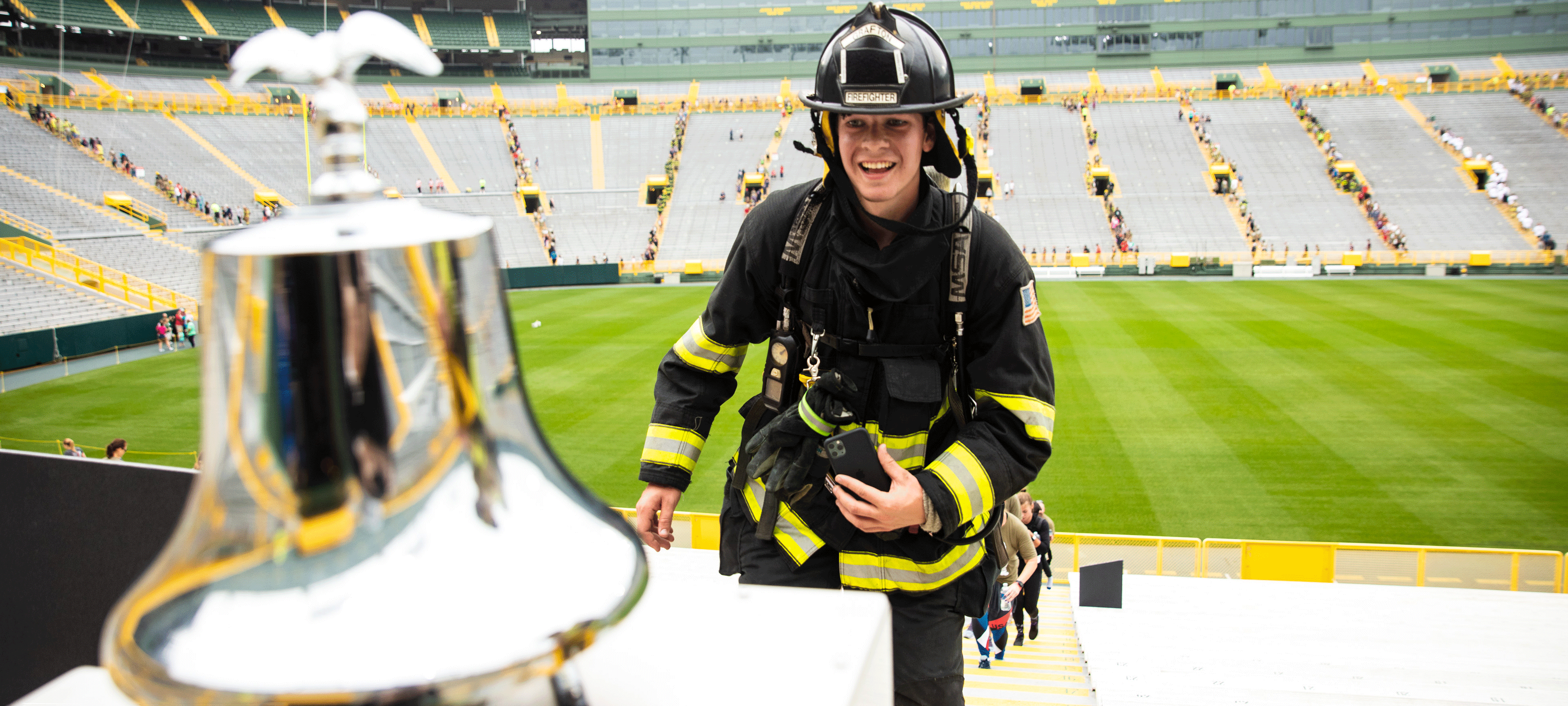 Firefighter ringing the bell at the 9/11 Memorial Stair Climb at Lambeau Field.